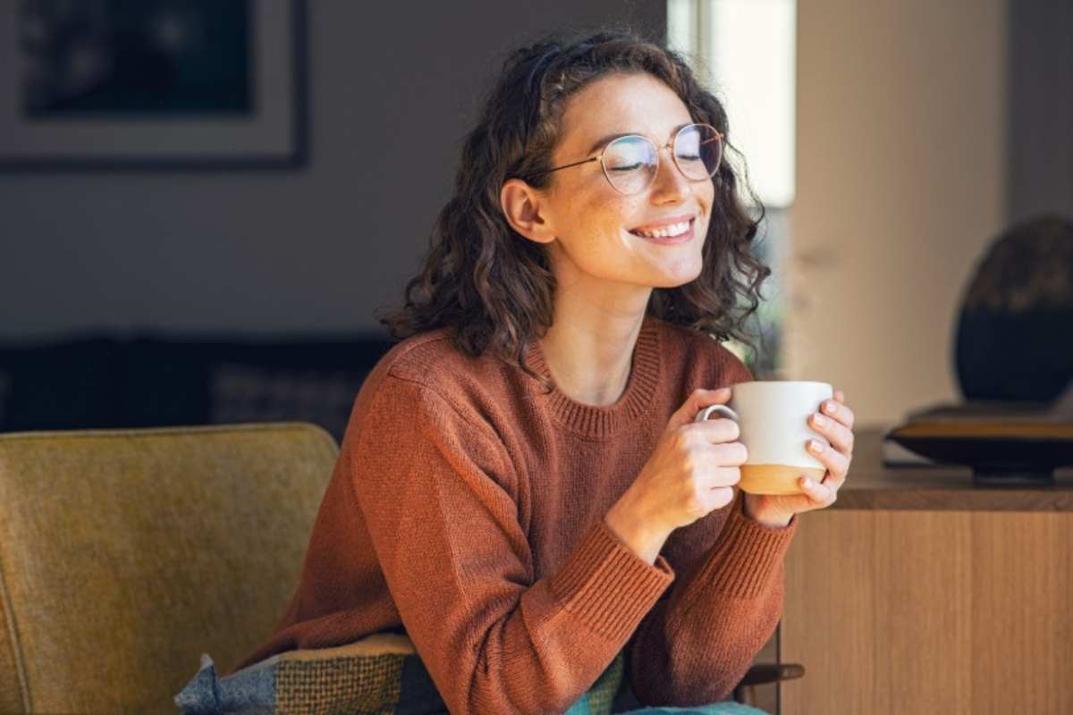 Donna beve un tè caldo sorridendo 